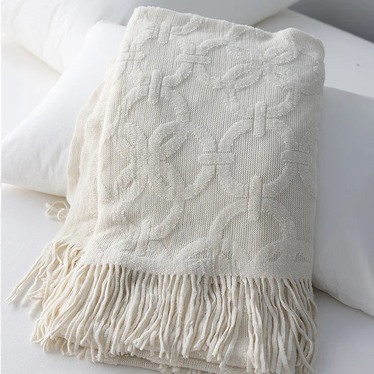 White knit throw folded over pillows, the raised rings and crossbars standing out from the ribbed ground