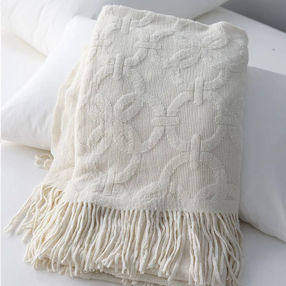 White knit throw folded over pillows, the raised rings and crossbars standing out from the ribbed ground