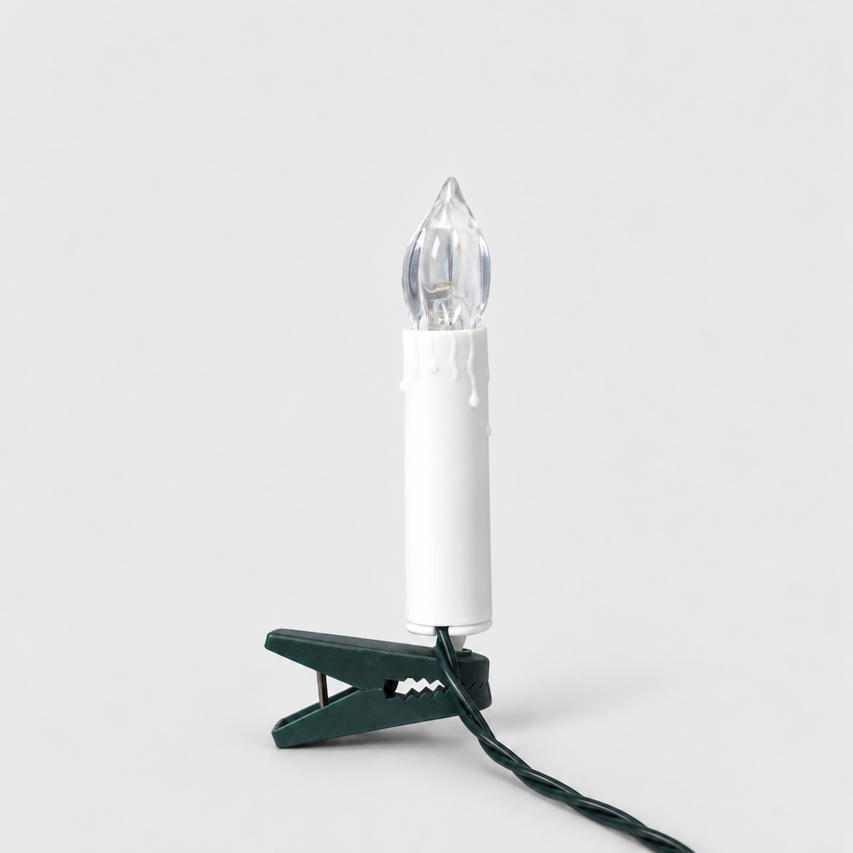 White clip-on LED Christmas tree candle with a wax drip edge and a clear flame-shaped cover on a dark green clip, on a light gray background