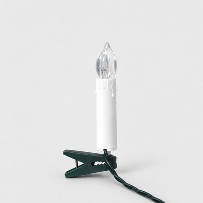 White clip-on LED Christmas tree candle with a wax drip edge and a clear flame-shaped cover on a dark green clip, on a light gray background