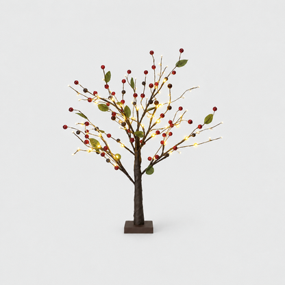 Tabletop Christmas twig tree with red berries, green leaves and warm LED lights on a dark brown trunk and square base, on a light gray background