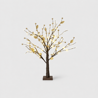 Tabletop Christmas twig tree with gold leaves, gold beads and warm LED lights on a dark brown trunk and square base, on a light gray background