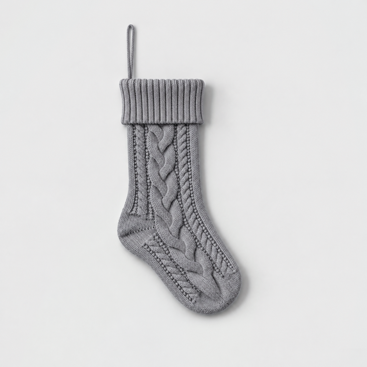 Gray cable knit Christmas stocking with a ribbed cuff on a light gray background