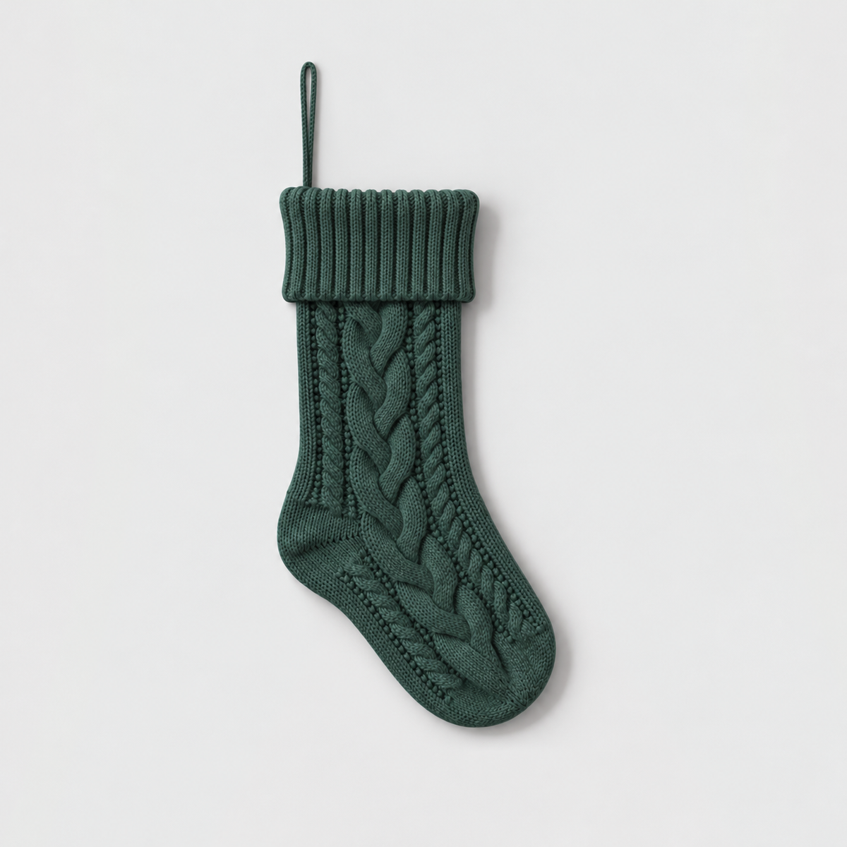 Deep green cable knit Christmas stocking with a ribbed cuff on a light gray background