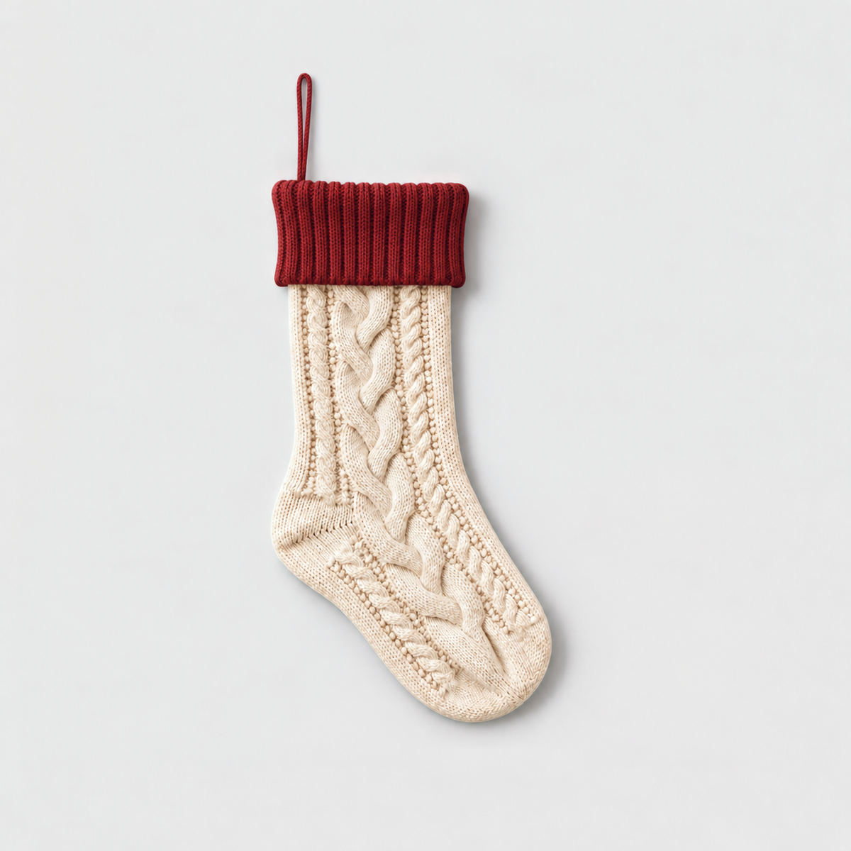 Cream cable knit Christmas stocking with a red ribbed cuff and red hanging loop