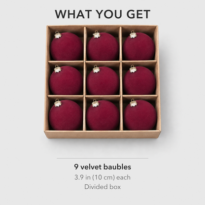 Nine burgundy velvet baubles in their divided box, one in each compartment