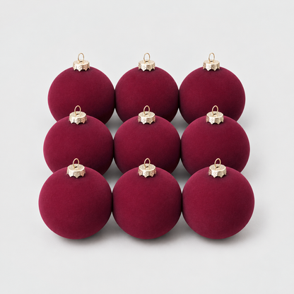 Nine burgundy velvet Christmas baubles grouped together on a light gray background