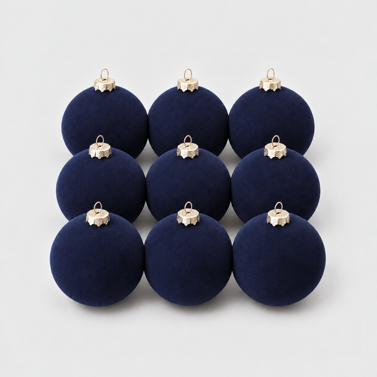 Nine navy velvet Christmas baubles grouped together on a light gray background