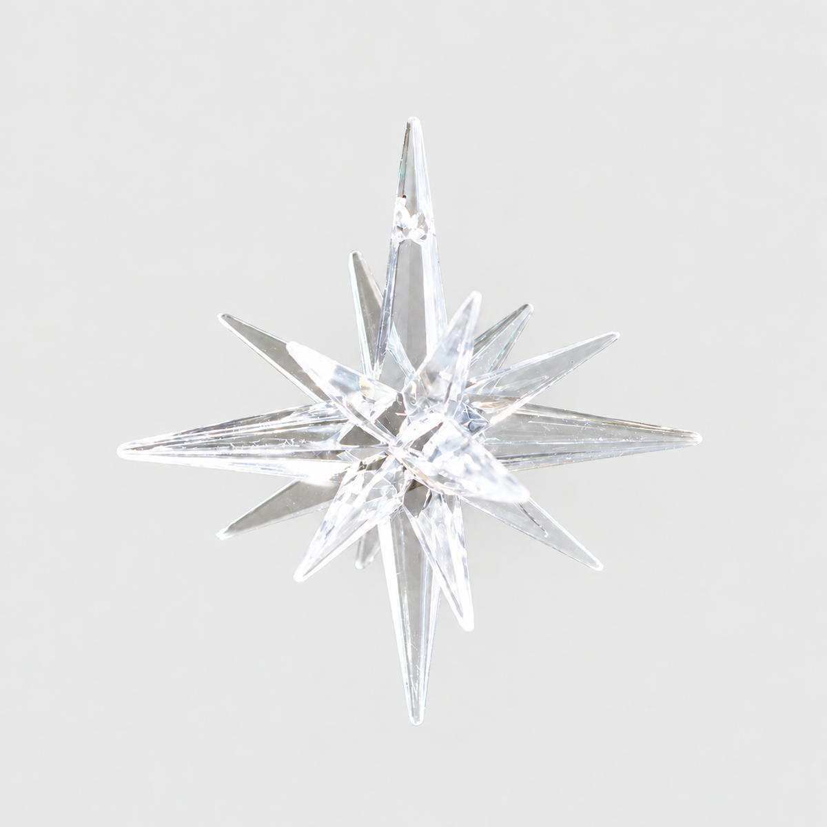 Clear faceted plastic star ornament on a plain light grey background