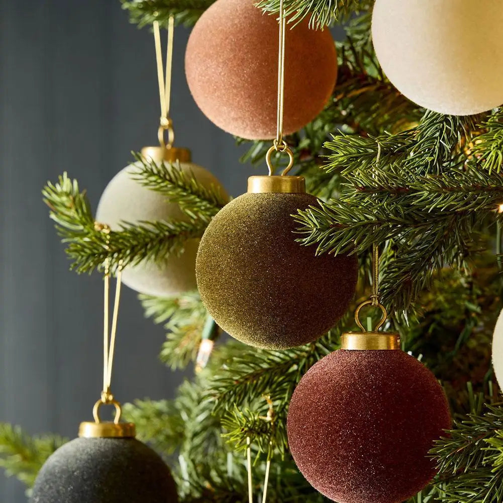 Close-up of olive, rust and cream velvet baubles hanging among fir branches