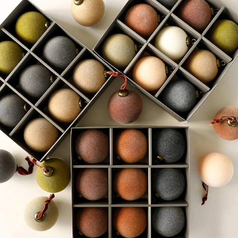 Open boxes of velvet baubles in muted colors with loose baubles and ribbon loops