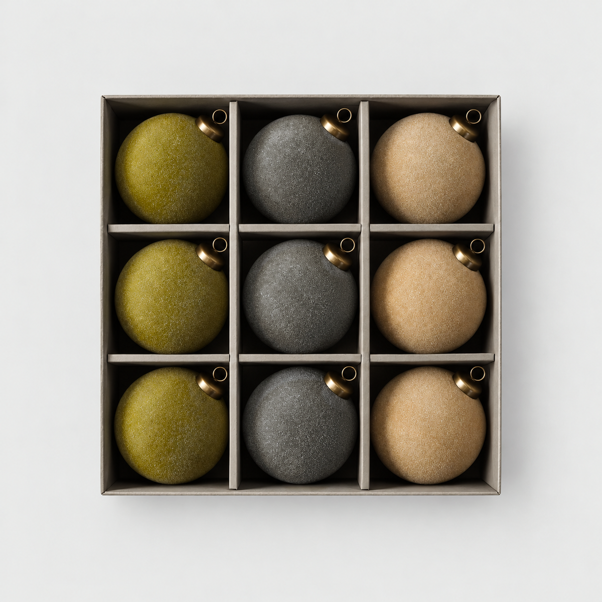 Open box of nine velvet Christmas baubles, three olive, three gray and three tan, on a light gray background