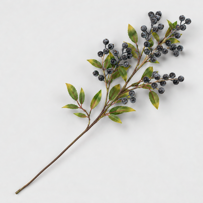 Artificial berry branch with slate blue berries and green leaves lying on a light gray background