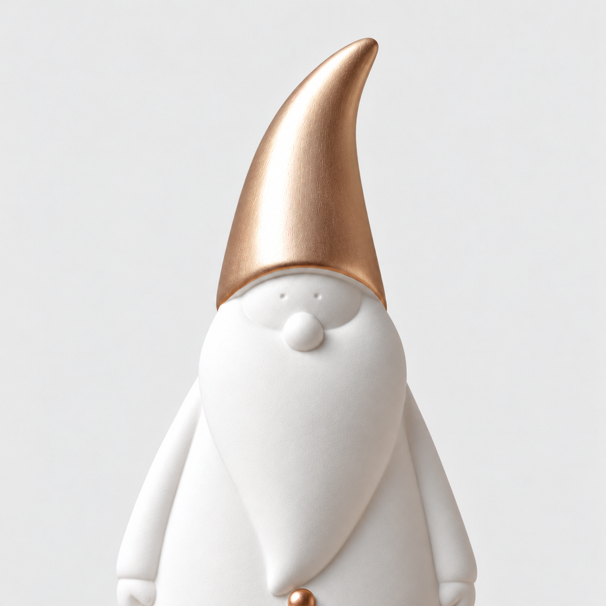 Close-up of the brushed rose gold hat, small dot eyes and round nose on a matte white ceramic Santa figurine
