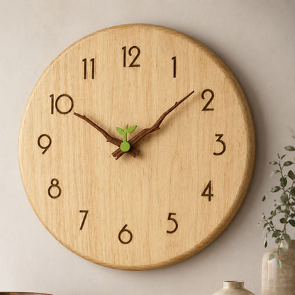Twig-hands wood wall clock seen close on a beige wall, with branch-shaped walnut hands and a small green sprout at the center