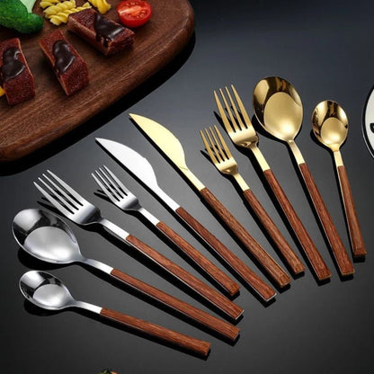 Silver and gold stainless steel cutlery with brown wood-grain handles fanned out on a dark table