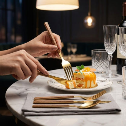 Gold cutlery with wood-look handles in use at a marble dinner table with crystal glasses