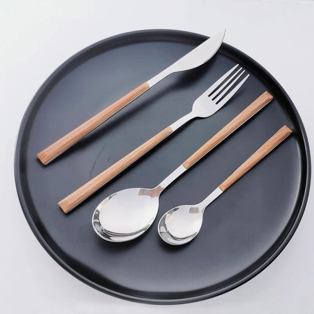 Silver knife, fork, soup spoon and teaspoon with wood-look handles on a round black plate