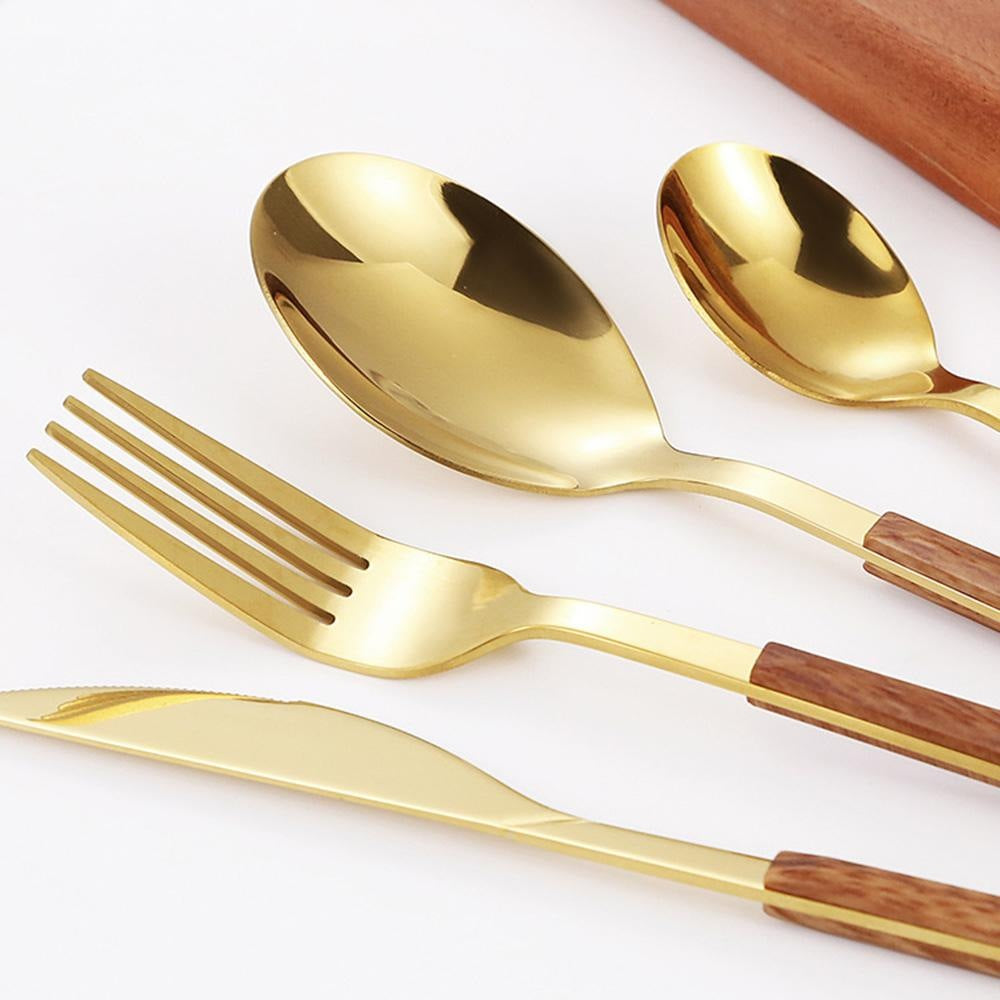 Close view of the gold spoons, fork and knife where the polished heads meet the wood-grain handles