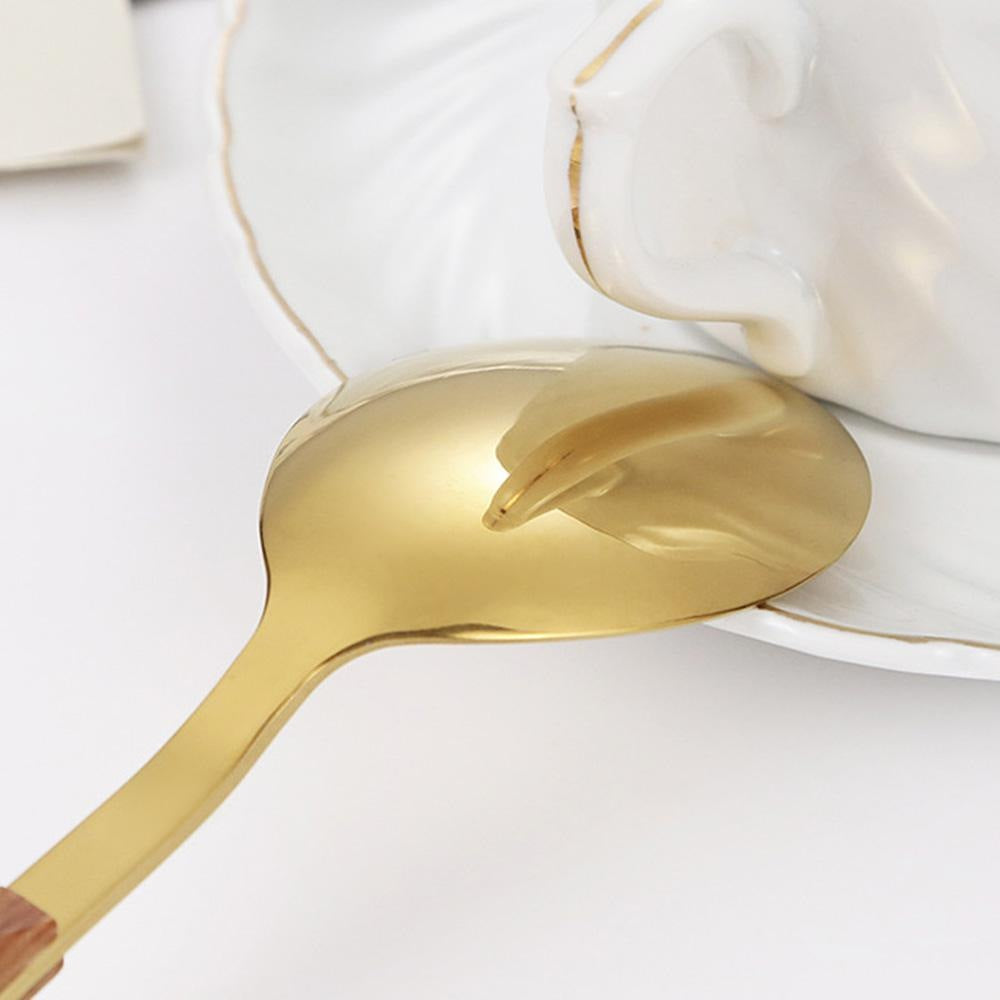 Close view of a gold soup spoon with a mirror polish resting on a white saucer