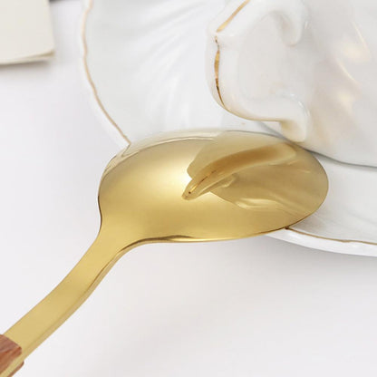 Close view of a gold soup spoon with a mirror polish resting on a white saucer