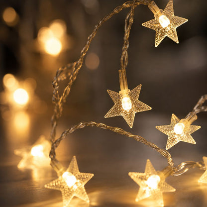 Close-up of clear dotted plastic stars glowing warm white on a twisted clear wire