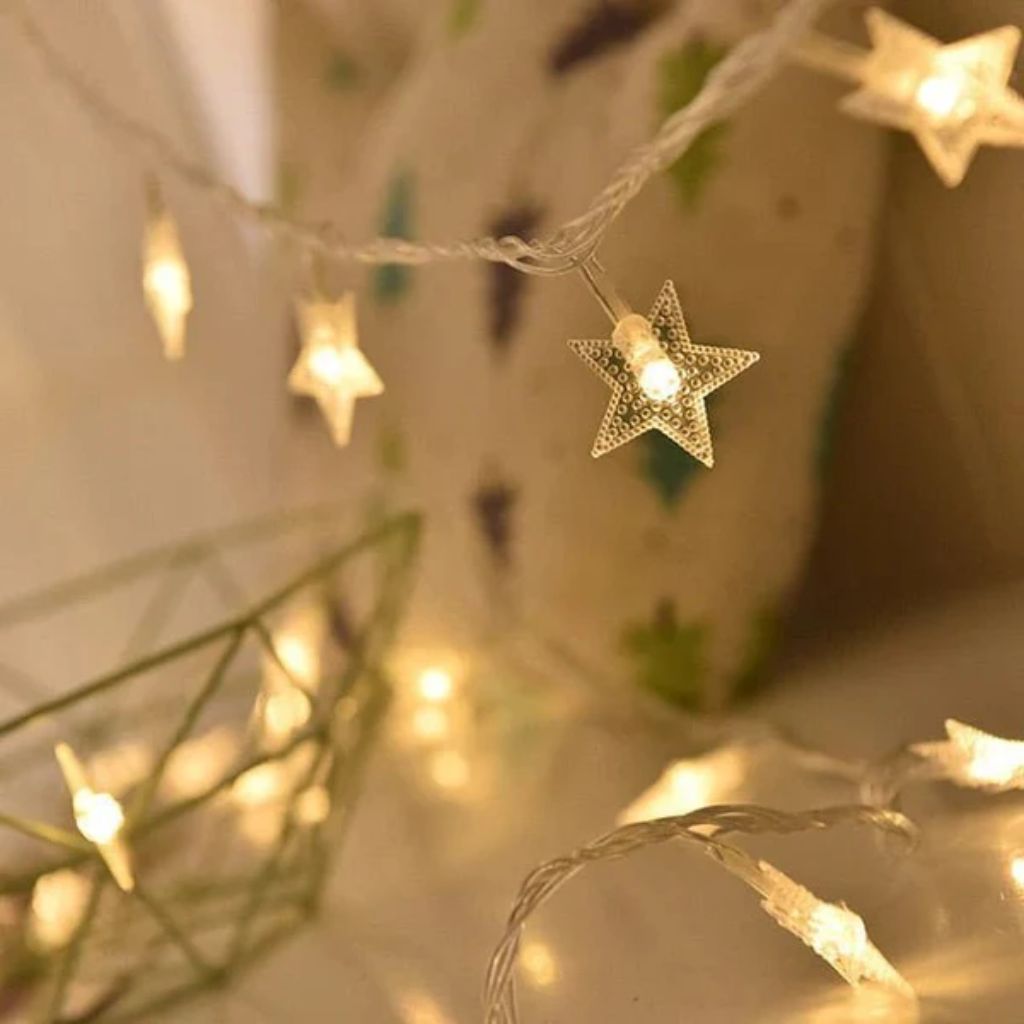 Clear dotted star lights hanging from a twisted clear wire, glowing warm white