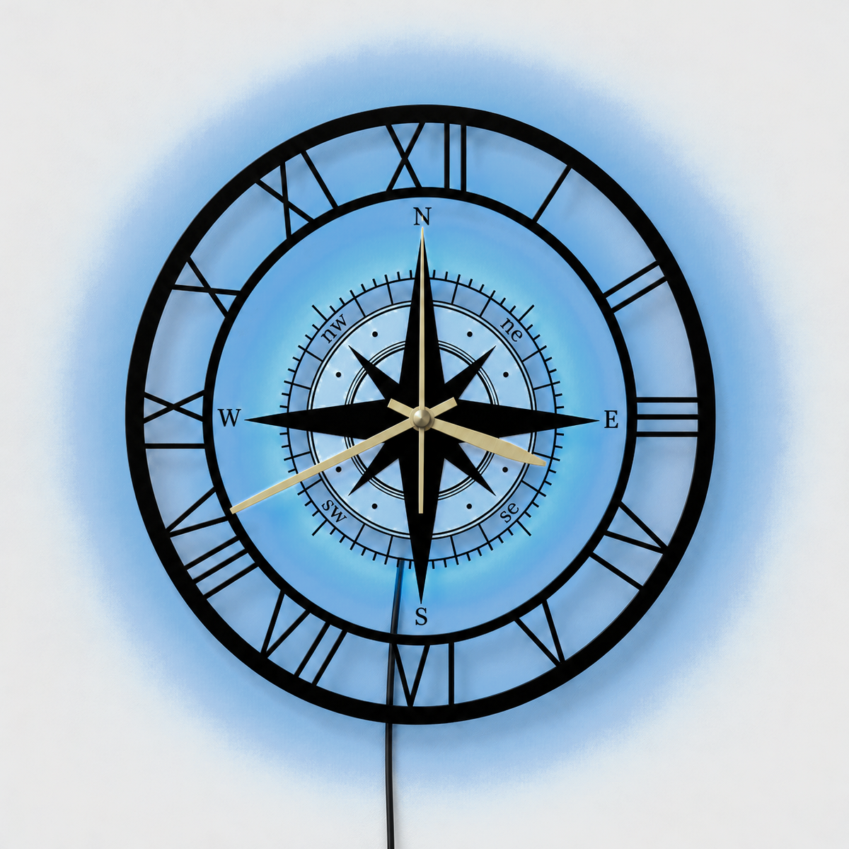 Compass wall clock with its LED backlight glowing soft blue behind the center, a thin black cable hanging below, on a light gray wall