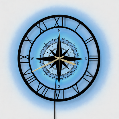 Compass wall clock with its LED backlight glowing soft blue behind the center, a thin black cable hanging below, on a light gray wall