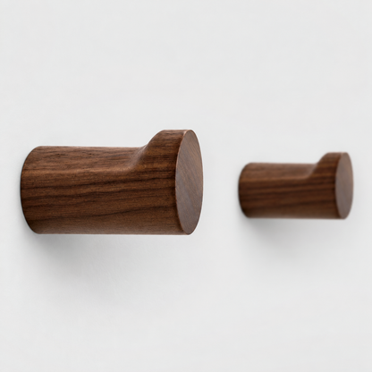 Close-up of walnut wall hooks showing the wood grain, the flat ledge on top and the raised lip at the end