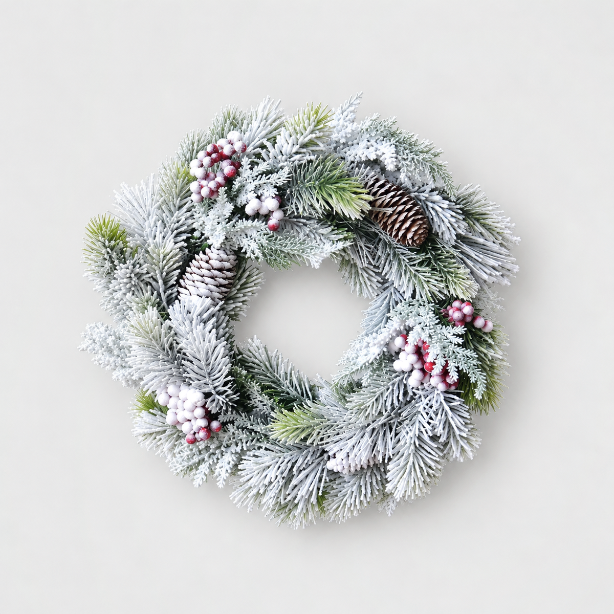 Large frosted pine wreath with red and white berries and pine cones, 16 inches across, on a light grey background