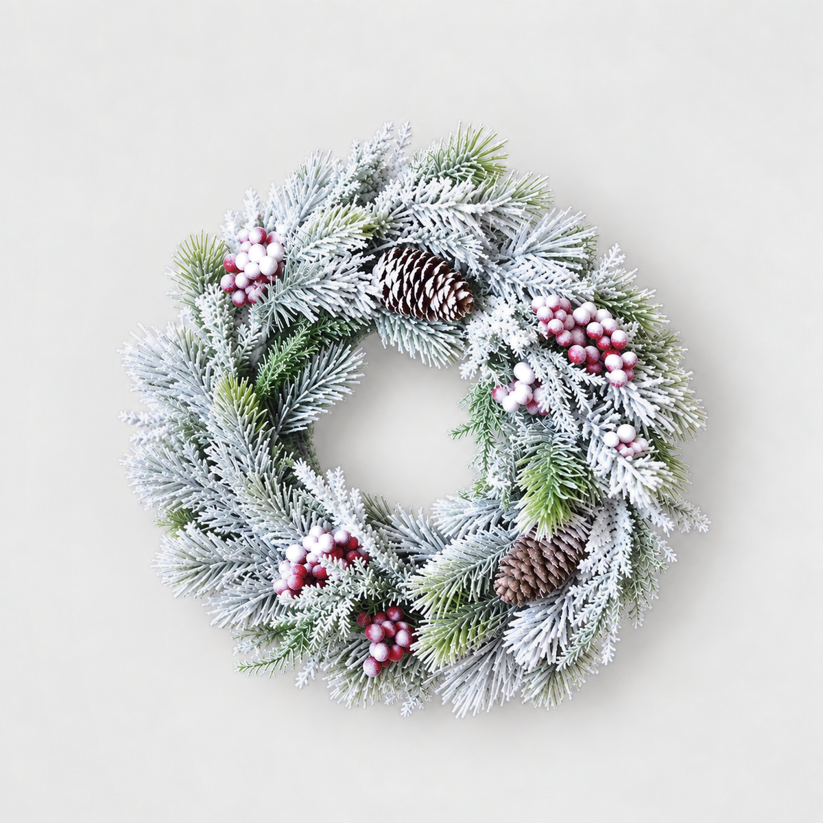 Small frosted pine wreath with red and white berries and pine cones, 12 inches across, on a light grey background