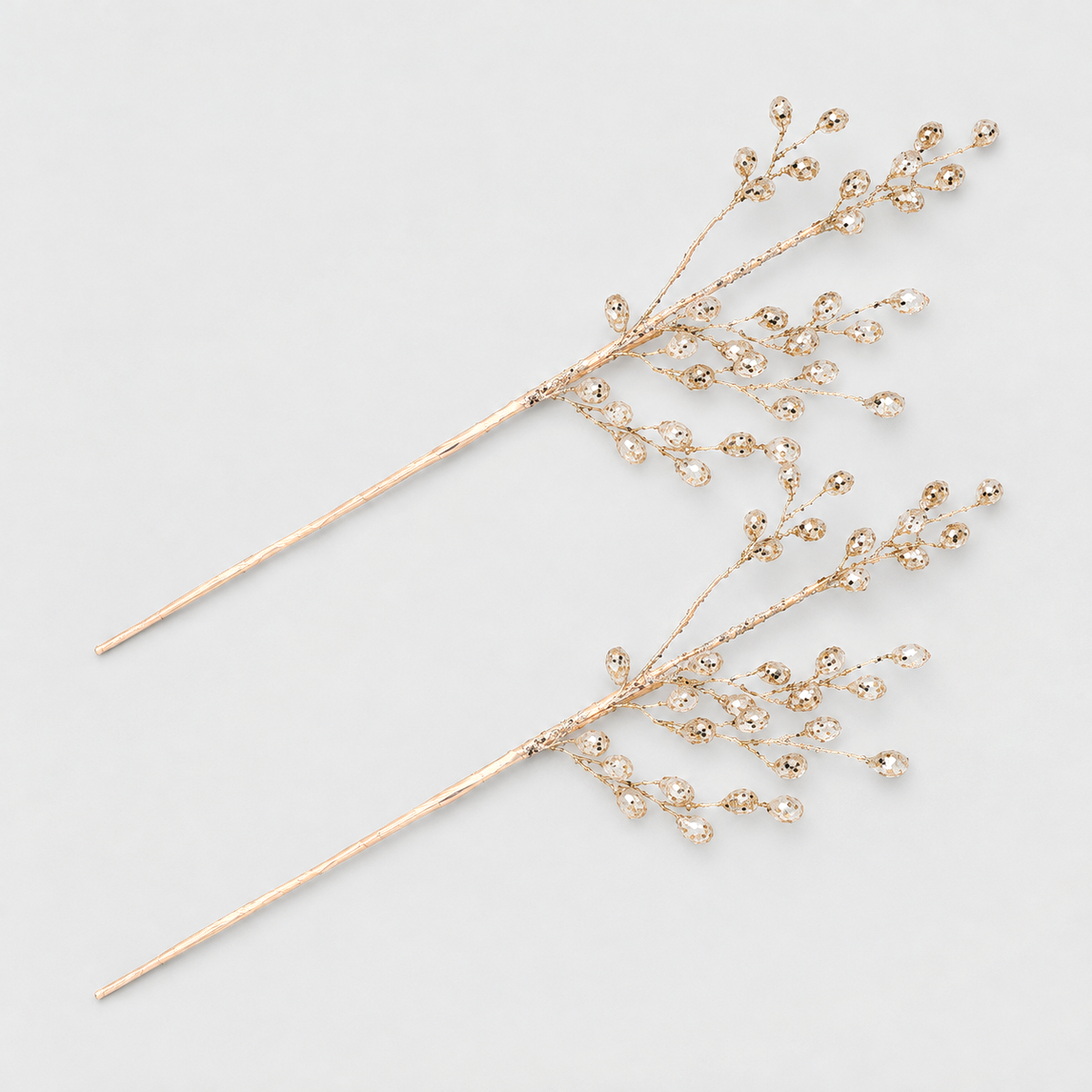 Two champagne gold bead branch picks with clear acrylic beads on a light gray background