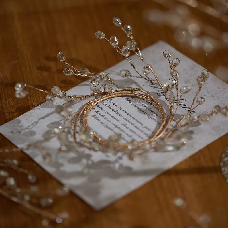 Close-up of the gold wire ring with clear crystal beads on sprigs, resting on a printed card