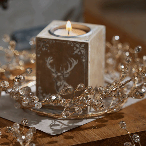 Crystal bead candle ring wrapped around a wooden tea light block with a lit tea light
