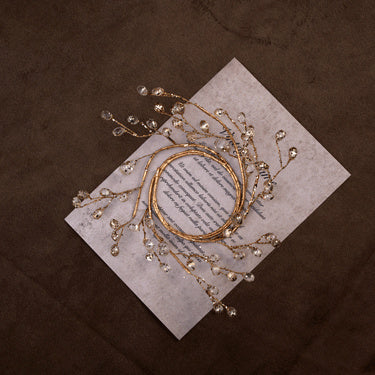 Small gold crystal bead ring on a printed card over dark brown linen