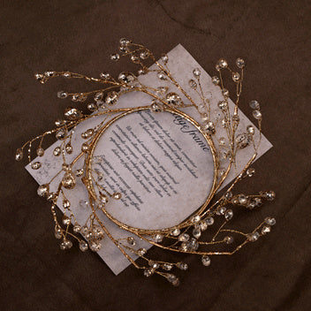 Large gold crystal bead ring on a printed card over dark brown linen
