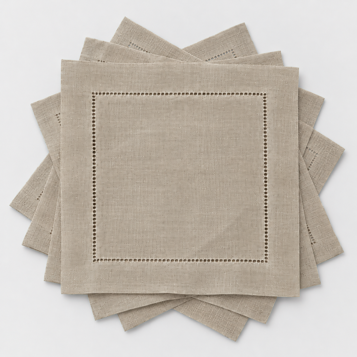 Six small taupe hemstitch cocktail napkins fanned out in a loose rotation on a light grey background