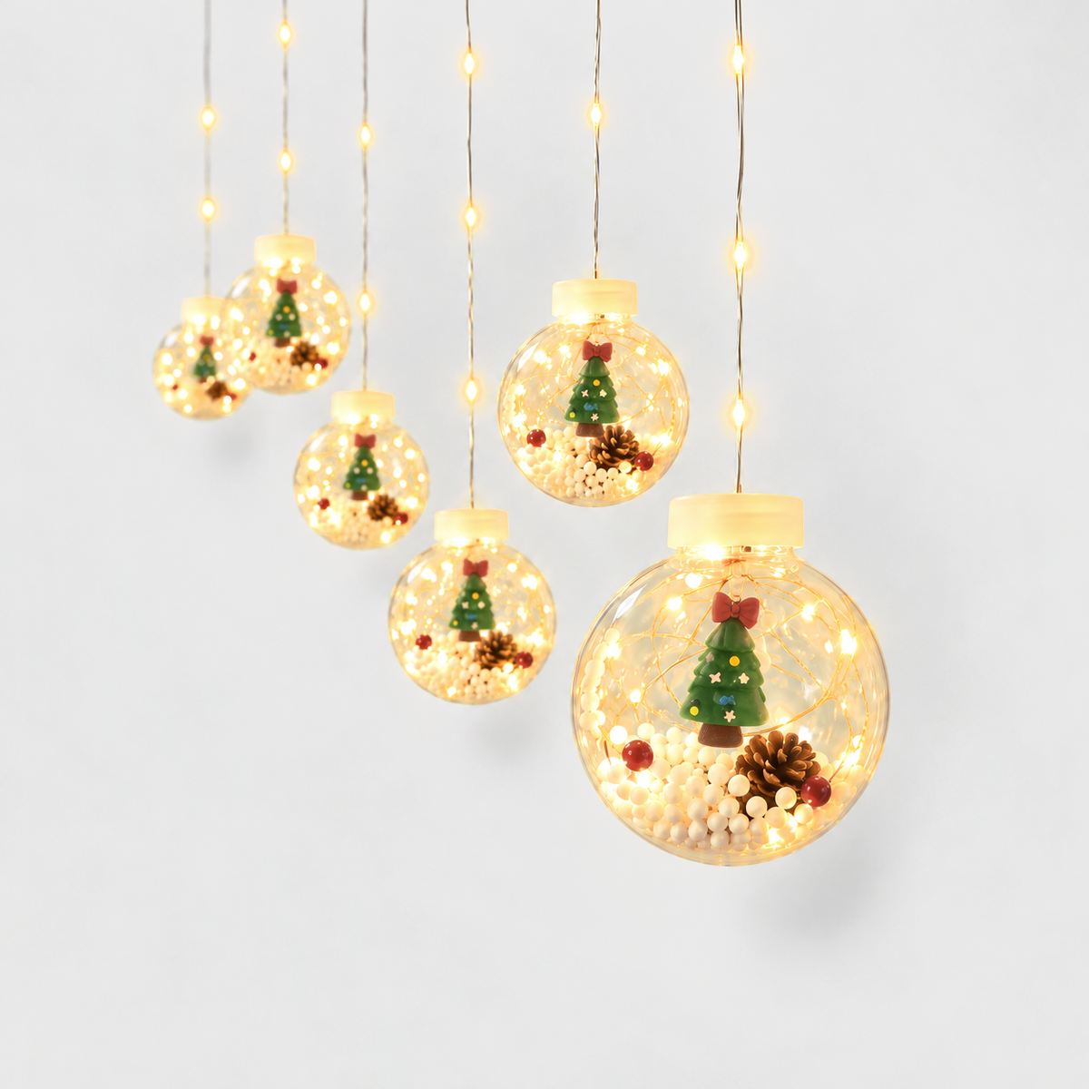 Christmas ball curtain lights with a little Christmas tree inside each clear globe, glowing warm white on a light gray background