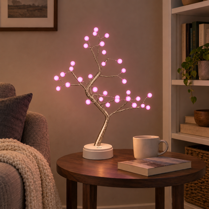 LED tree lamp with pale branches and glowing pink pearl lights on a side table beside an armchair