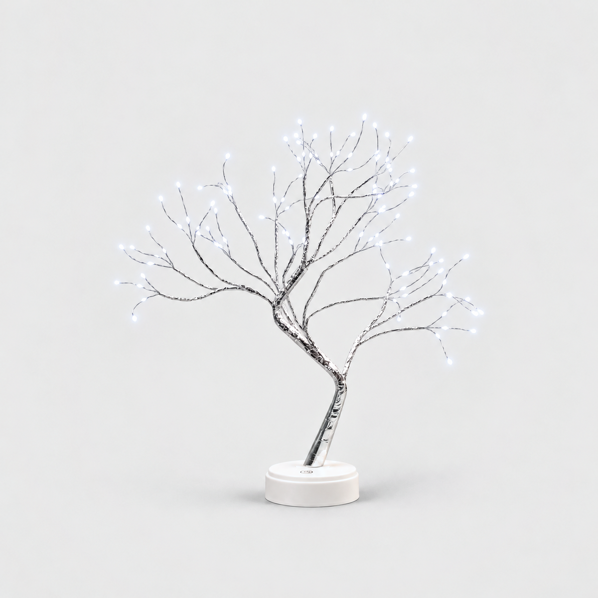 LED tree lamp with silver branches and cool white fairy lights, lit, on a white round base