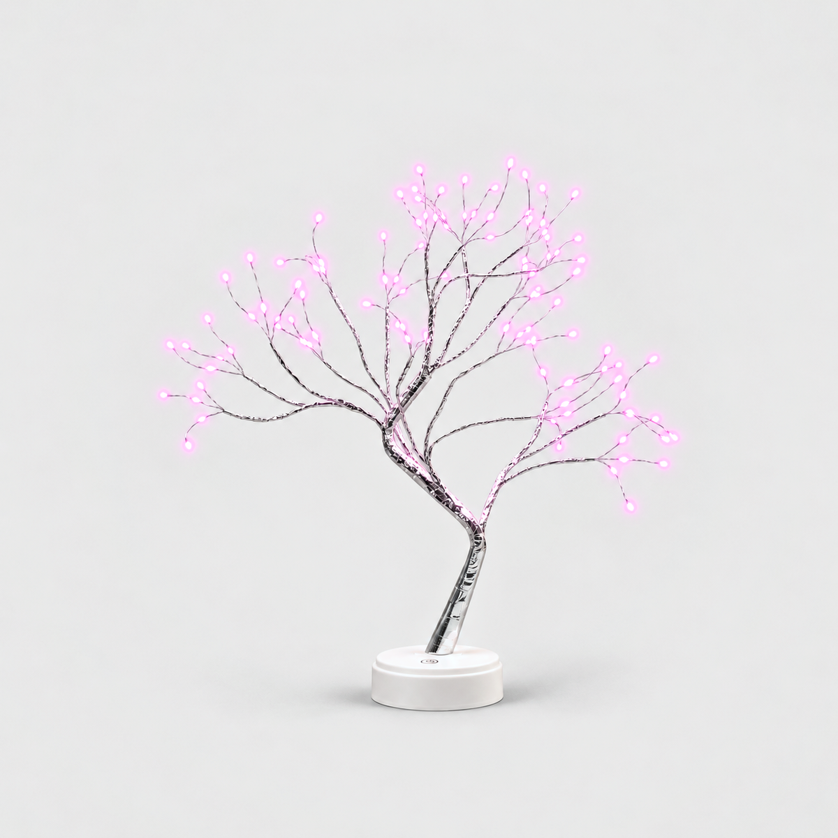 LED tree lamp with silver branches and pink fairy lights, lit, on a white round base