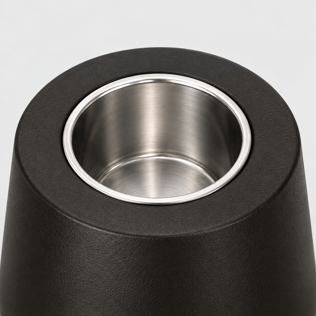 Close-up of the stainless steel burn cup seated in the flat matte black top of the fire pit