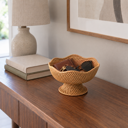 Small rattan bowl on a pedestal holding keys, a wallet and sunglasses on a walnut entry table