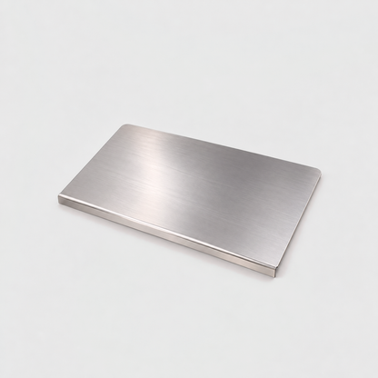 Small stainless steel chopping board on a light gray background, the lip folded down along its front edge