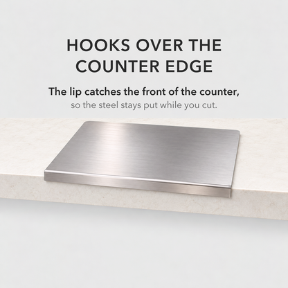 Steel chopping board with its folded lip hooked over the front edge of a stone counter