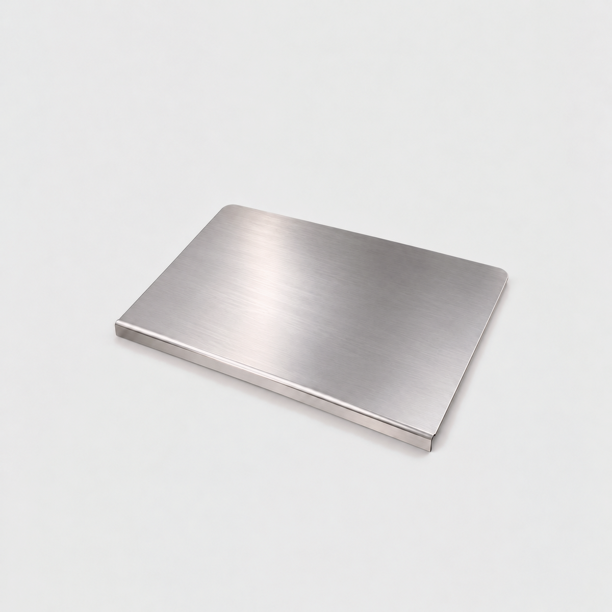 Large stainless steel chopping board on a light gray background, the lip folded down along its front edge