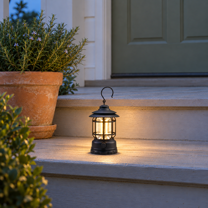 Black vintage lantern glowing warm on wooden porch steps at dusk