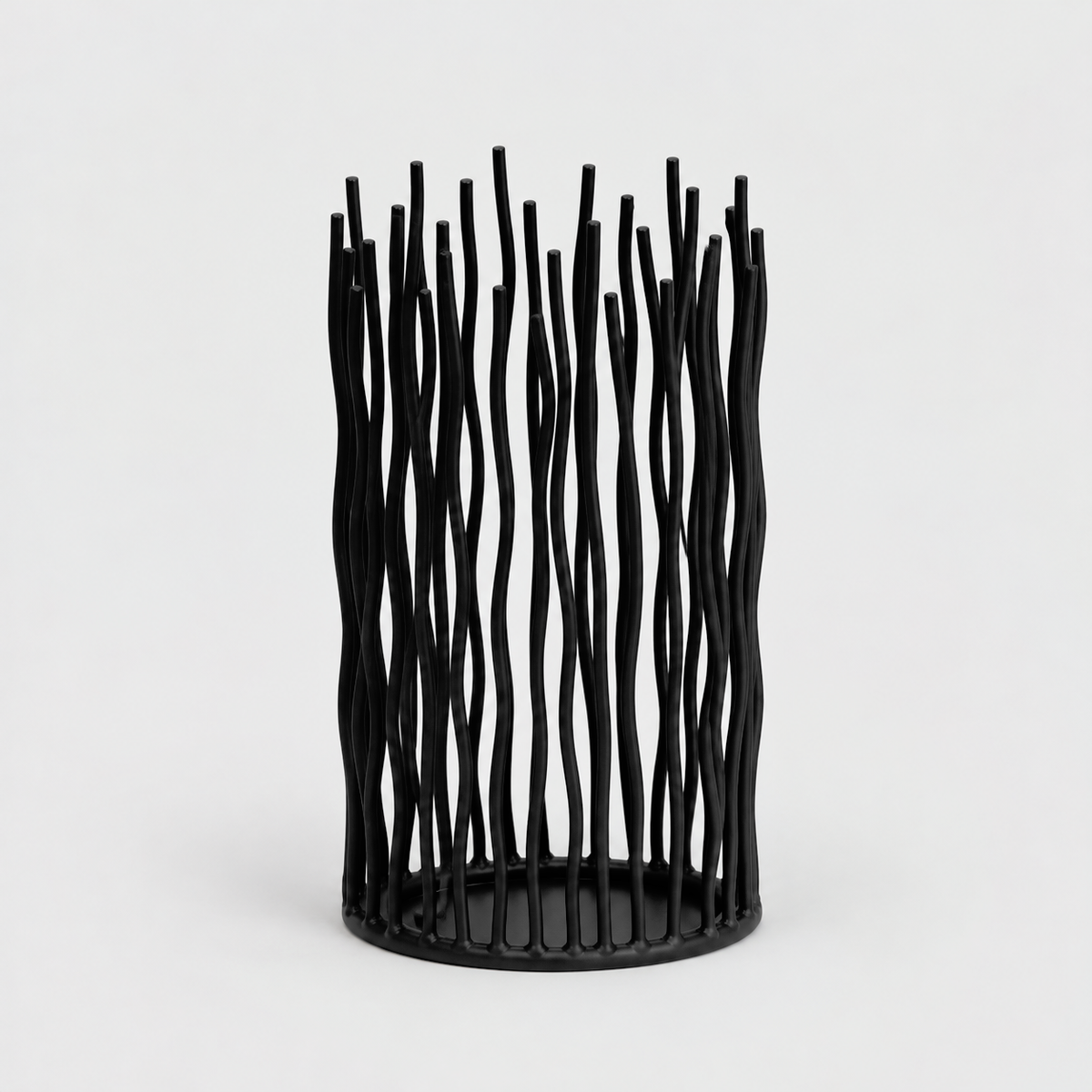 Small black iron pillar candle holder with wavy vertical rods on a light gray background