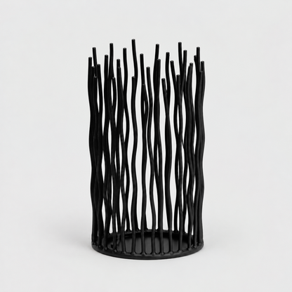 Small black iron pillar candle holder with wavy vertical rods on a light gray background